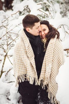 A guy and a girl in warm clothes and scarves on a walk in the snowy forest and in the field