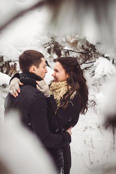 A guy and a girl in warm clothes and scarves on a walk in the snowy forest and in the field