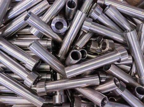 full frame abstract indistrial background of pile of shiny steel tubes after cnc turning operations