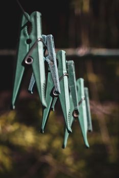 Old plastic clothespins on a rope hanging outside house, toned green, vintage look