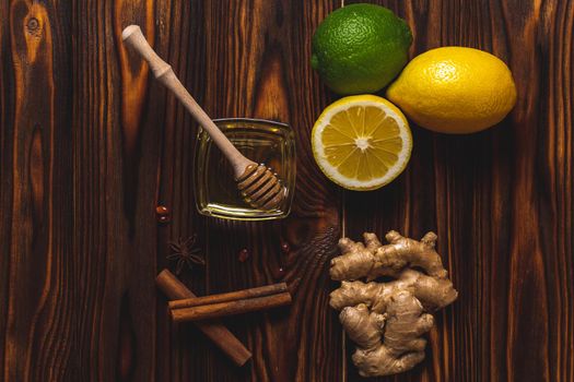 Ginger, lemon, honey, cinnamon on a dark wooden background. Cold cure recipe and healthy food