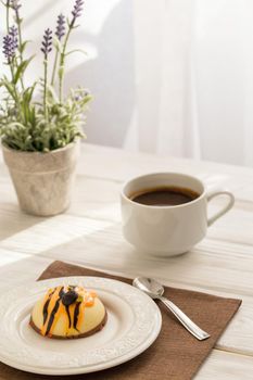 Still life with coffee, cake and a bouquet of lavender on white wooden table. Breakfast in the morning sun