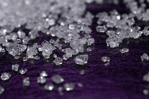 White sugar crystals on a dark violet background, macro, close-up