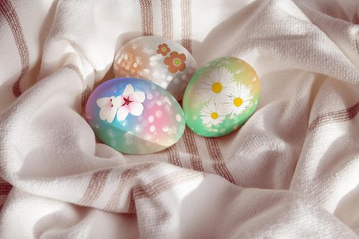 Painted easter fresh chicken eggs on a linen towel under a soft sunlight. Scandinavian rustic style.