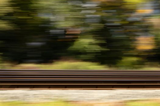 Railroad high dynamic motion blur, abstract blurred background with green trees, side view