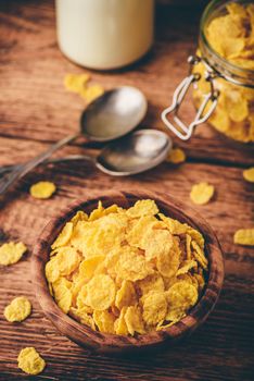 Corn flakes in a wooden bowl on rustic surface