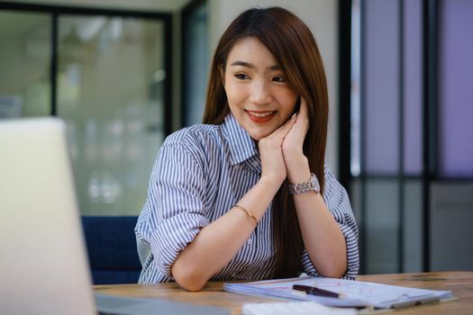 Joyful businesswoman sitting at desk looking at laptop screen talking with friend make informal video call