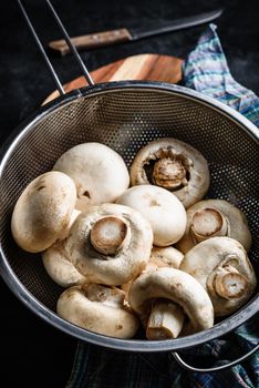 Fresh white button mushrooms in metal colander