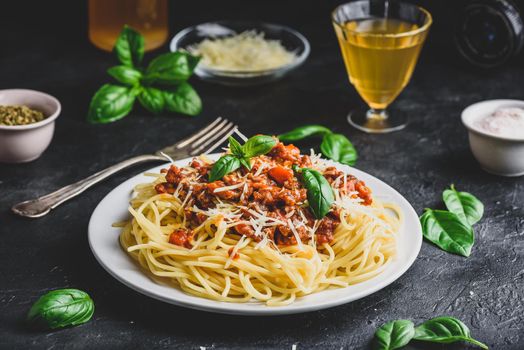 Spaghetti with bolognese sauce, grated parmesan cheese and fresh basil leaves