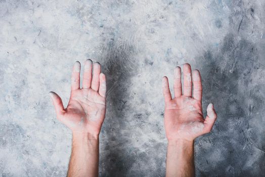 Man hands covered with paint on gray concrete wall background