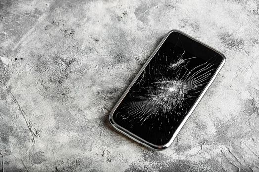 Smartphone with cracked screen over concrete background