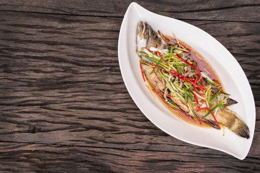 Steamed fish with soy sauce on wooden table.