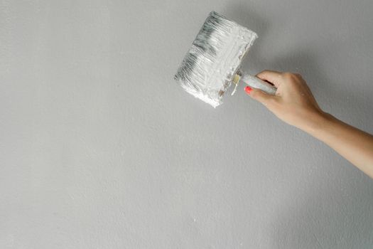 Hand holding paint brush on wall for painting