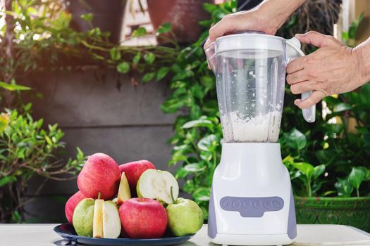 Hand of people are using an electric blender to making fresh apple and guava juice.