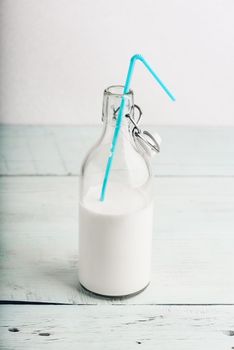 Milk in glass bottle with blue straw