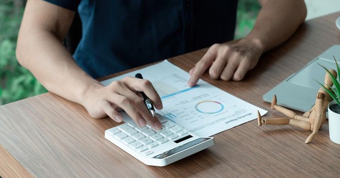 Businessman working with financial data hand using calculator and writing make note with calculate. Business financial and accounting concept.