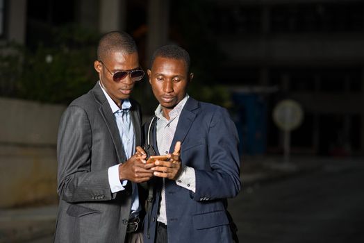 Small group of business people talking outdoors using mobile phone after work
