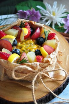 Close up summer fruits topping on new york cheesecake serve on wooden board decorated with flowers on background