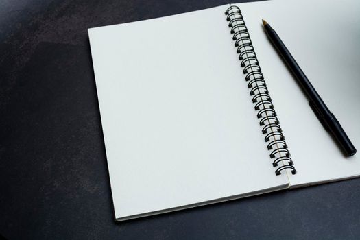 White notebook and pen on dark background. Space for text