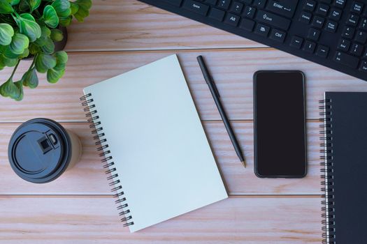 Homeoffice with keyboard, notepad, pen, coffee and smartphone on wooden table. Space for text. Flat lay, top view