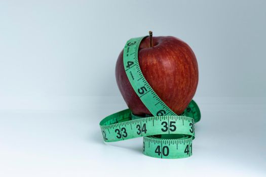 Blurred red apple with measuring tape isolated on white - Diet concept