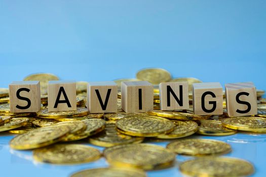 Savings text on wood block with a pile of gold coins