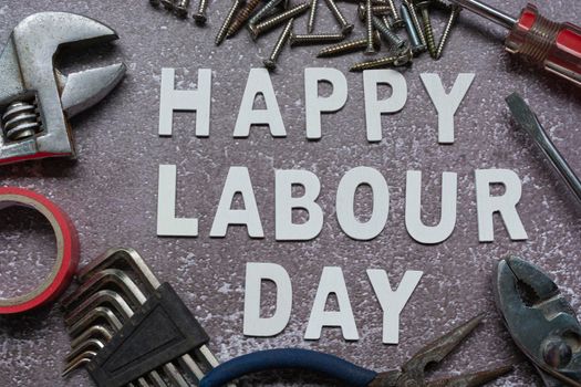 Happy labor day text with repair equipment and many handy tools on grunge grey concrete background