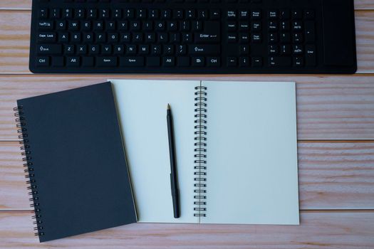 Homeoffice with keyboard, note books and pen on wooden table. Space for text. Flat lay, top view