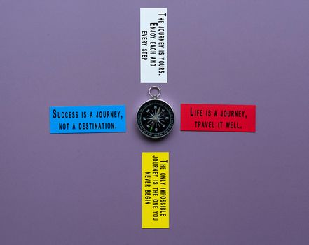 Text on colorful paper with classic round compass on purple background - Motivational quote about journey