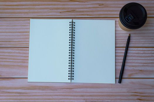 Note book with pen and coffee on wooden table. Space for text. Flat lay, top view