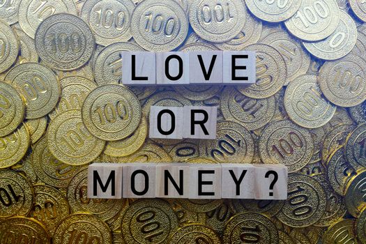 Love or money text on wood block with a pile of gold coins