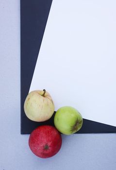 White and blue paper sheets with three colorful ripe apples