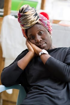 portrait of African woman with a scarf sitting in a chair behind her sales display