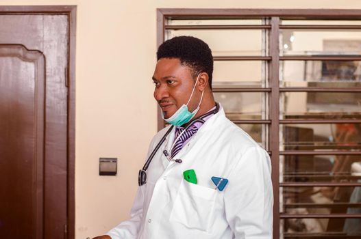 a young doctor standing in his office and looking at the camera.
