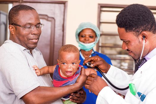 a young man catches his baby during the doctor examines him at the hospital.