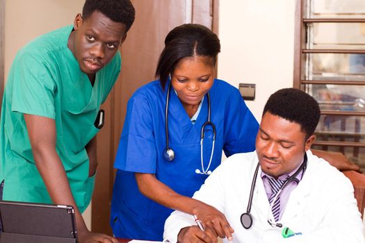 group of mixed doctors with tablet computers meeting at medical office and looking together on the chart of the chief doctor in his office