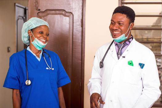 a doctor and his nurse standing in a room laughing.