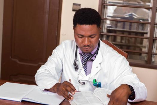 young doctor sitting at desk writing a prescription in a notebook