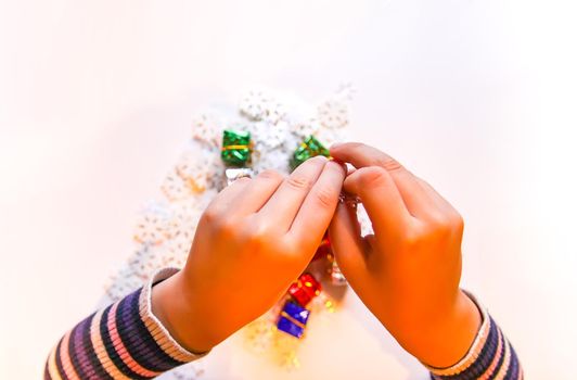 Small paper snowflakes and bright colorful gift boxes in child's hands. Cristmas and New Year gift decoration process.