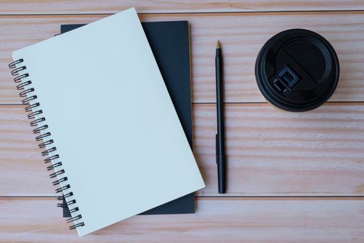 Note books, pen, disposable and coffee cup on wooden table. Space for text. Flat lay, top view