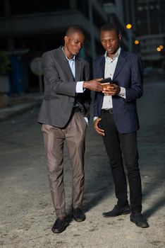 Young business men with suit walking down the street at night and using a mobile phone