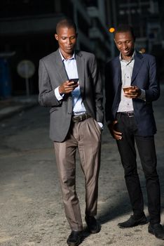 Young business men with suit walking down the street at night and using a mobile phone