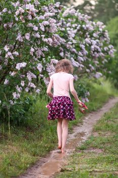 Barefoot girl walks through a puddles of water after the summer rain in countryside.