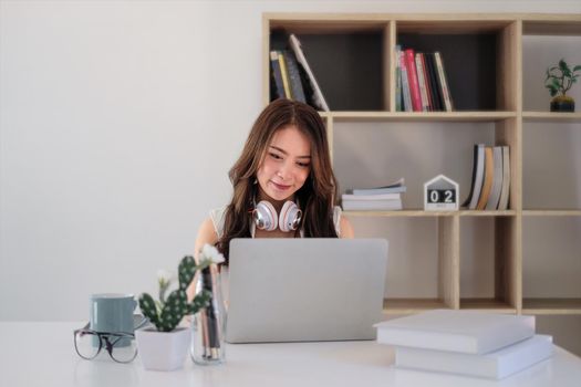 cheerful asian woman wear headset using laptop computer for video stream conference call teach online