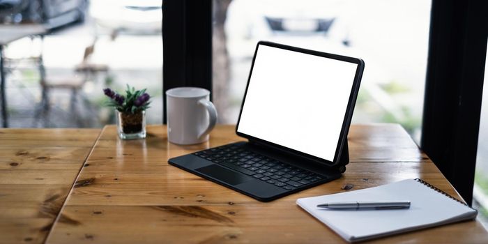 Mockup image of a black tablet with white blank screen on wooden desk