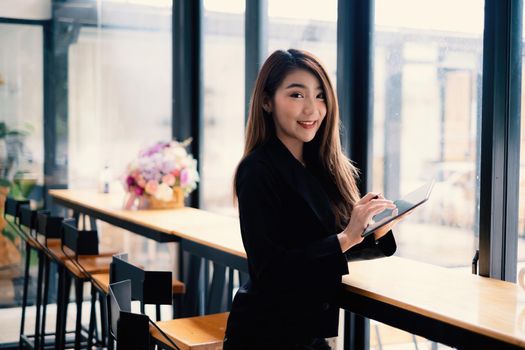 Joyful businesswoman sitting at desk holding digital tablet.