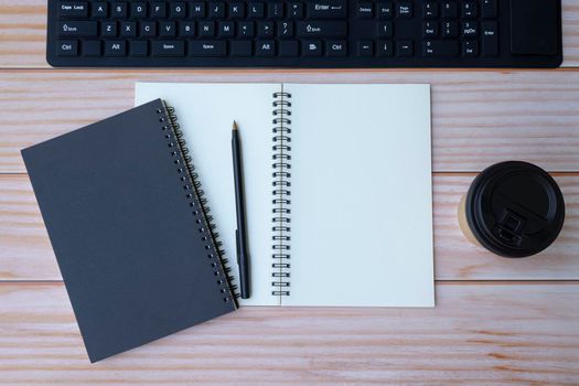 Home office space with keyboard, note books, pen and disposable coffee cup on wooden table. Space for text. Flat lay, top view